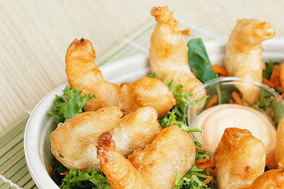 A bowl of fried food with a side of dipping sauce.