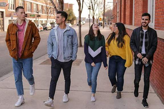 Five people walking on a sidewalk.
