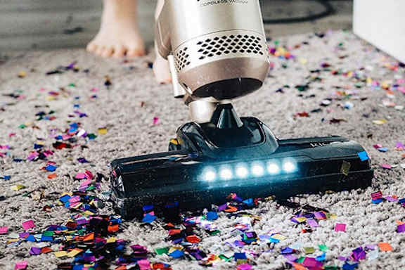 A hair dryer is on a carpet with confetti scattered around it.