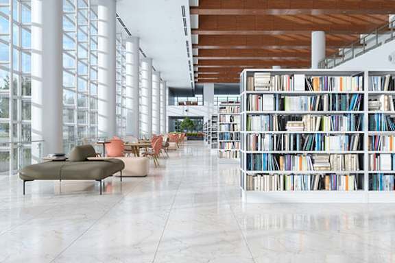 A library with a lot of books on the shelves and a white marble floor.