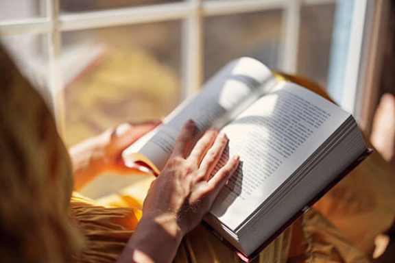 A person is reading a book with a white cover.