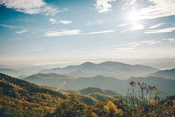 A beautiful mountain landscape with the sun shining through the clouds.