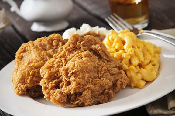 A plate of fried chicken and macaroni and cheese with a fork on the side.