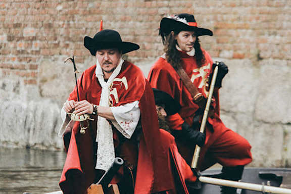 Two people dressed in red and black are rowing a boat.
