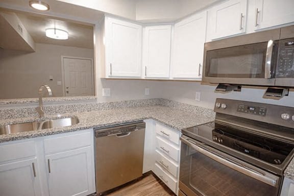 a kitchen with white cabinets and stainless steel appliances