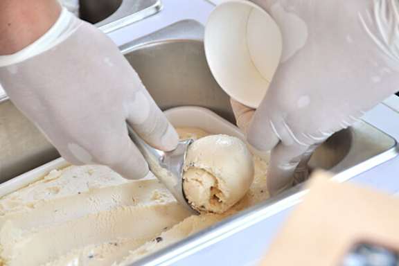 A person scooping vanilla ice cream with a spoon.