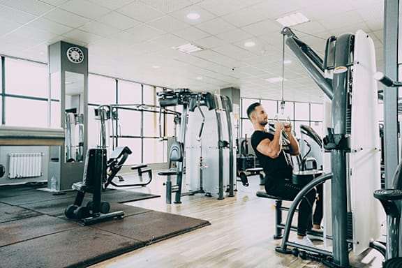 A man is working out in a gym with a variety of equipment.
