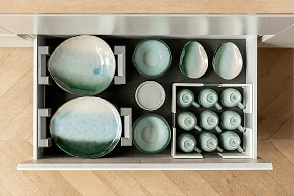 A drawer with ceramic dishes in various shapes and sizes.