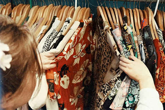A woman is looking at clothes on a rack.