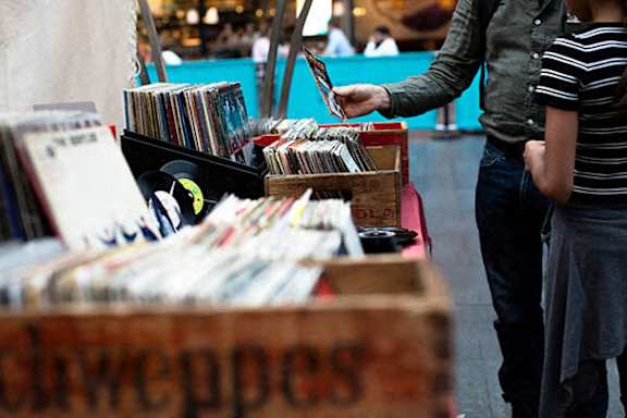 A man is selling CDs in a box labeled "Cowpops".
