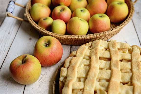 A basket of apples and a pie with lattice crust.