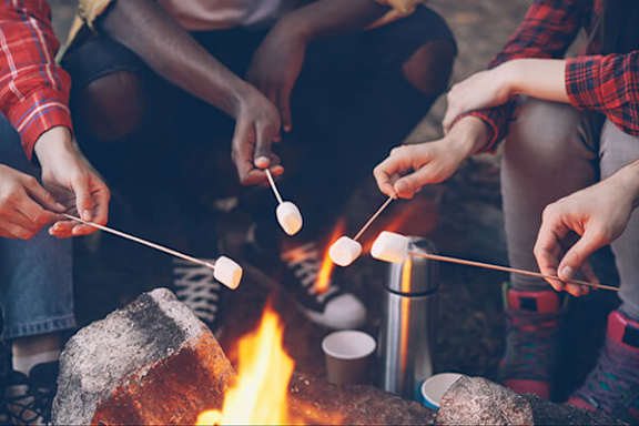 A group of people roasting marshmallows over a campfire.