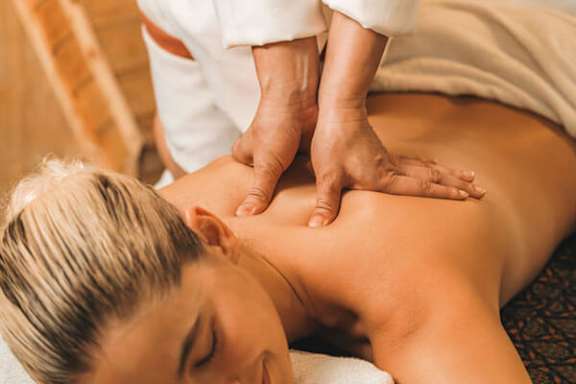 A person receiving a back massage from a masseur.