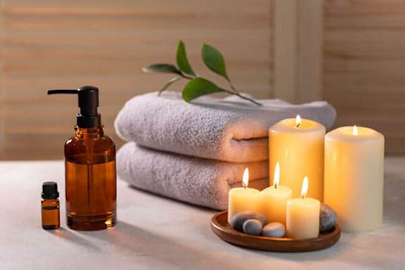 A spa setting with candles, towels, and a bottle of oil.