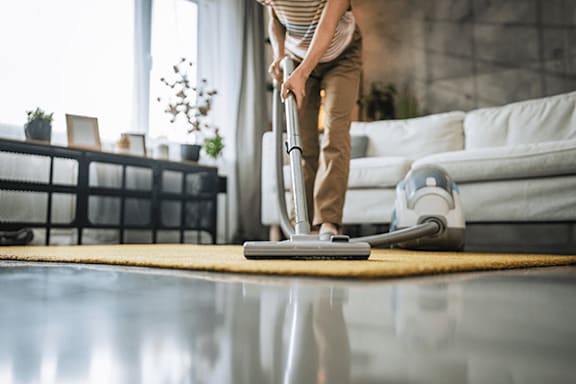 A person vacuuming a shiny floor in a modern living room.