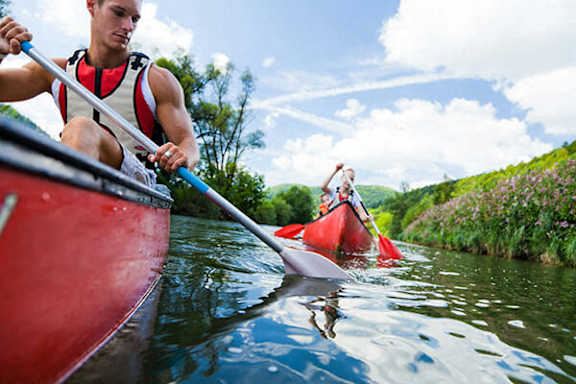 A man in a red kayak paddles down a river.