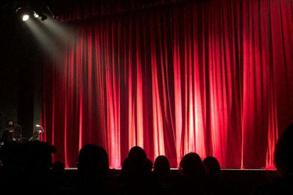 a red curtain at a theater with a spotlight on it