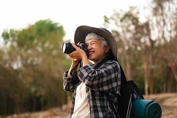 A man in a hat is taking a photo with a camera.