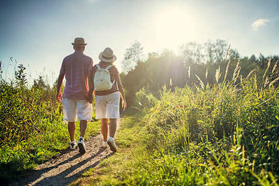 A man and a woman are walking on a path in a field.