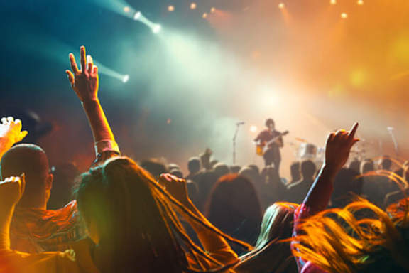 A crowd of people at a concert with their hands raised in the air.