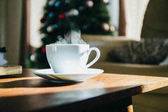a cup of coffee on a table with a christmas tree
