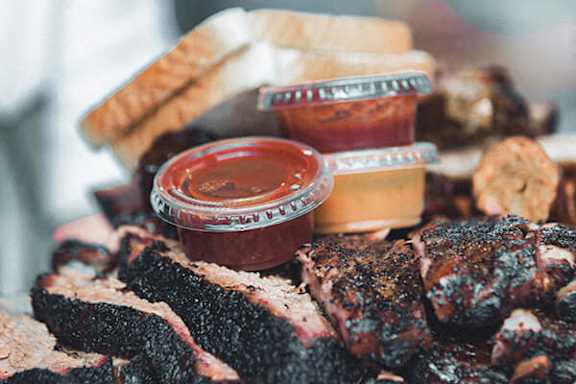 A plate of barbecued ribs with two sauces.