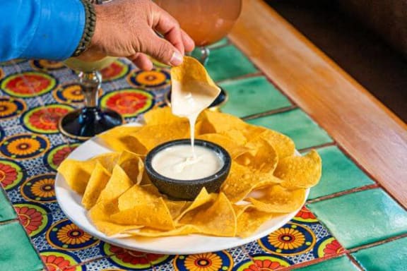 a person dipping nacho chips into a dipping sauce
