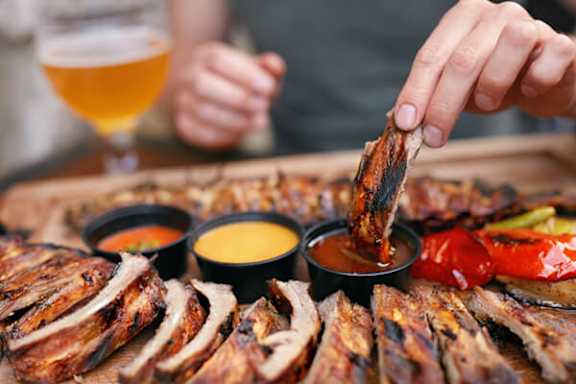 A person is dipping a piece of meat into a sauce.