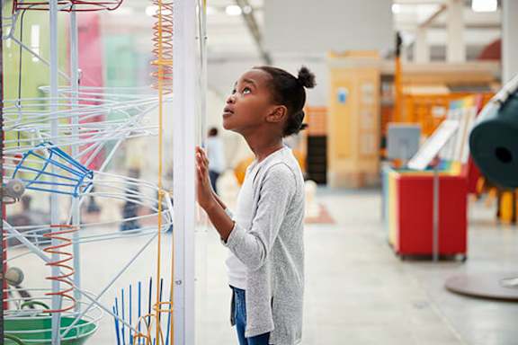 A girl is looking at a colorful structure.