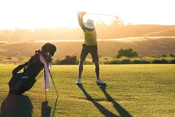 a woman swinging a golf club on a golf course