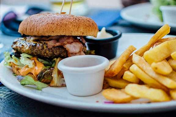 A sandwich with bacon and lettuce on a plate with fries and sauce.