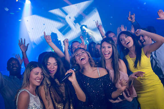 A group of people are dancing and singing along to a performer at a concert.