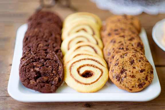 A white plate with four different cookies on it.