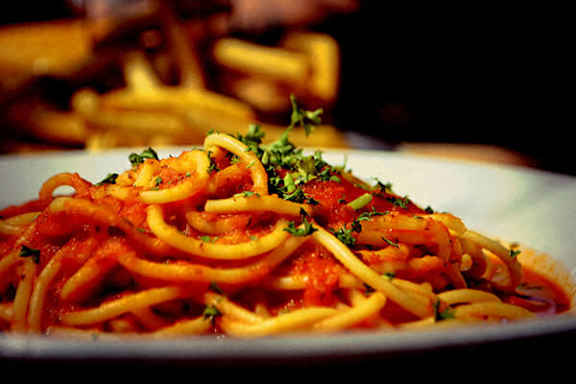 A plate of spaghetti with tomato sauce and garnished with parsley.