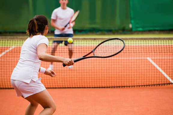 A woman in a white dress is playing tennis.