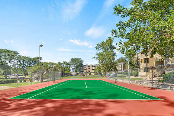 A tennis court with a green surface and red boundary lines.