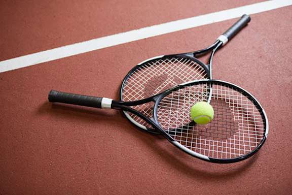 Two tennis rackets on a tennis court with a ball on the net.