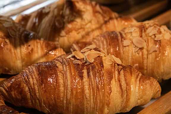 A close up of a croissant with almond slices on top.