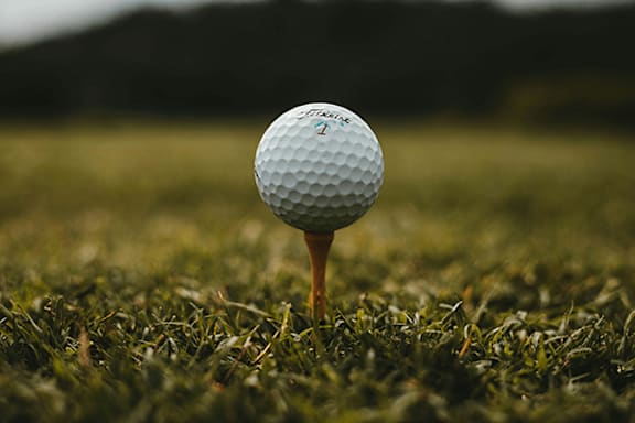 A golf ball on a tee on a grassy field.