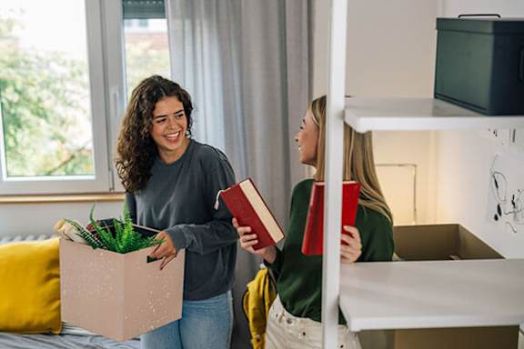 Two women are unpacking boxes in a room.