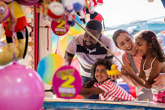 A family playing a game at an amusement park.