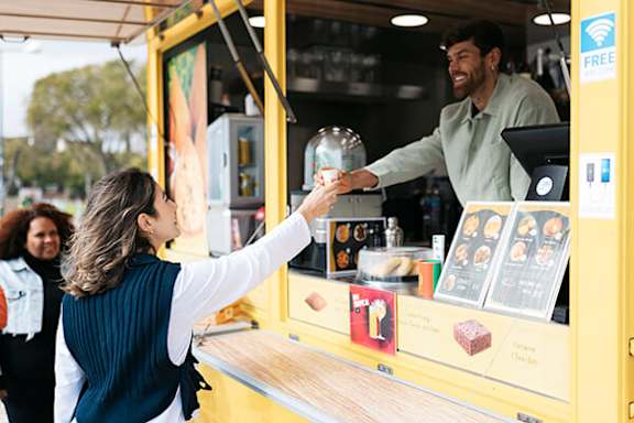 A woman is handing a jar to a man behind a counter.