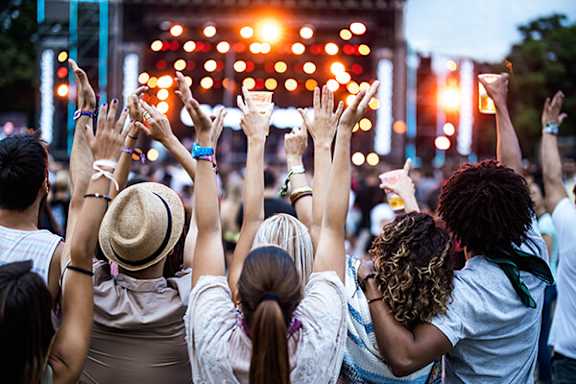 A group of people at a concert with their hands raised in the air.