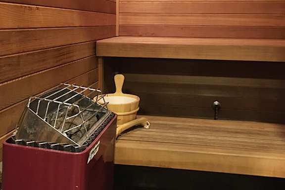 A wooden sauna with a red container and a white container on the bench.