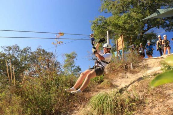 a woman riding a zip line on a hill
