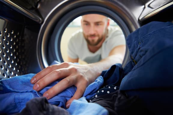 A man is looking into a washing machine.