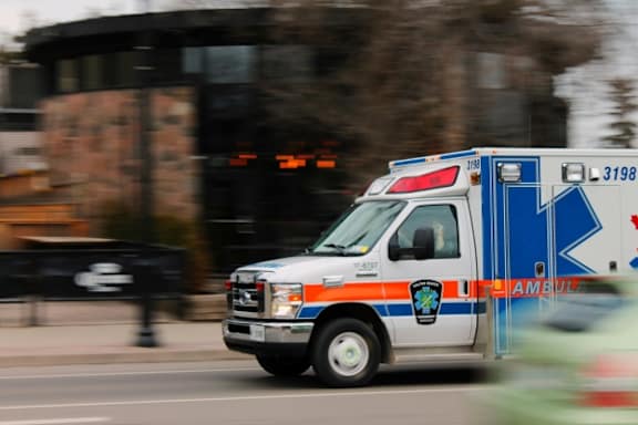 A</br>blue</br>and</br>orange</br>ambulance</br>is</br>driving</br>down</br>the</br>street.