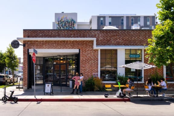 a brick building with people sitting at tables in front of it