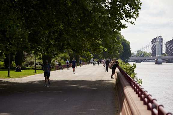 A group of people are walking along a path next to a river.