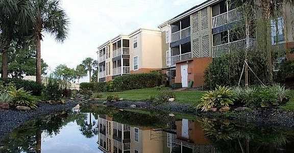 A building with a green roof is reflected in the water.